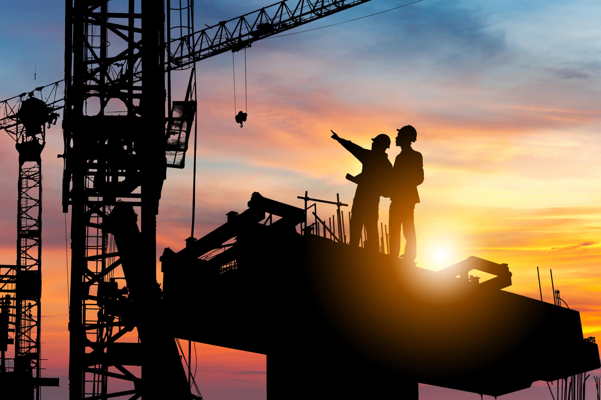 Silhouette of two men, working in twilight on top of a skyscraper