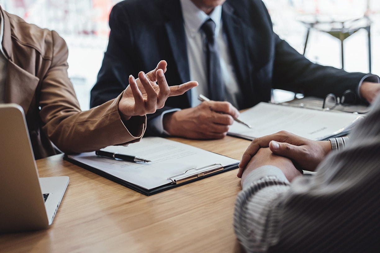 Two senior manager reading a resume during a job interview, Employer interviewing to ask young male job seeker for recruitment talking in office.