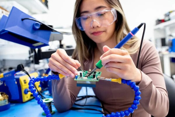 Woman using instrument in lab to solder a microchip